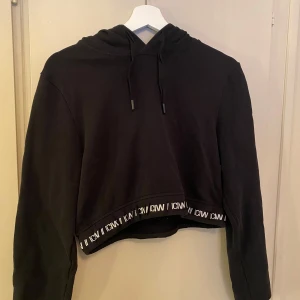 Svart croppad hoodie från ICANIWILL - Snygg svart croppad hoodie från ICANIWILL med justerbar huva och elastisk kant med logotyp. Inga tecken på användning, skriv för fler bilder😊