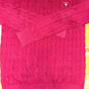 Röd stickad tröja från Gant - Säljer en snygg röd stickad tröja från Gant med kabelstickat mönster. Tröjan har långa ärmar och en rund halsringning. Perfekt för kyliga dagar! I bild fyra syns ett litet hål i ena armen som ej syns tydligt när man har på sig tröjan.