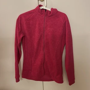 Rosa fleecetröja från Everest - Säljer en mysig rosa fleecetröjan från Everest med dragkedja framtill. Perfekt för kyliga dagar med sin mjuka och varma känsla. Tröjan har långa ärmar och en hög krage för extra värme.