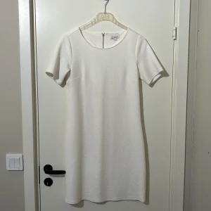Vit klänning från Bondelid  - Snygg vit klänning från Bondelid i storlek S. Den har en enkel och stilren design med korta ärmar och dragkedja bak. Perfekt för en elegant look.