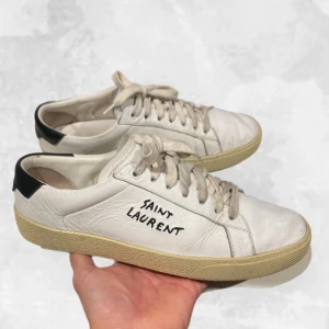 Saint Laurent skor vita - Skohylla rensning. •Saint Laurent Court Classic Sneakers. Riktigt snygga skor som har använts men tagits väl hand om. Creases finns men inga större skador annars! Storlek 40, fits 40-41. Dom är givetvis äkta, har kvitto på mail om det skulle vara intressant. •Pris bara skorna: 2 100 kr. •Pris skorna, YSL box & kort: 2 500 kr. Hör av dig vid frågor eller funderingar, mvh Oliver;)