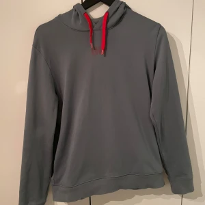 Grå/blå hoodie från Hugo - Snygg Grå/blå hoodie från Hugo med röda detaljer. Hoodien är i grymt skick och sitter mycket bra, priset är ej hugget u sten och ställ gärna frågor!😀