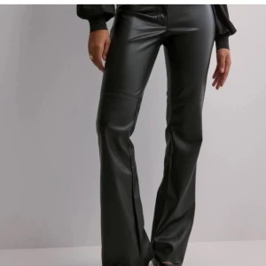 Lågmidjade skinnbyxor - Snygga svarta byxor i skinnimitation från Nelly. De har en låg midja och en bootcut-stil som ger en trendig look. Strl 32 men lite större i stoleken + stretch så passar nog även 34&36. Använda 1 gång. De är slutsålda på hemsidan.