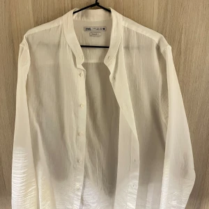 Vit linneskjorta från Zara - Säljer en stilren vit skjorta i linne från Zara i regular fit. Skjortan har en klassisk design med knappar framtill och är tillverkad i ett lätt och bekvämt material. Perfekt för både vardag och festliga tillfällen. Passar bra till både jeans och kostymbyxor.