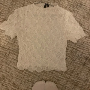 Vit blus med mönster - Säljer en superfin vit blus med ett vackert  mönster. Den har korta ärmar och en luftig passform, perfekt för både vardag och fest. Materialet känns mjukt och bekvämt mot huden. Passar perfekt till både jeans och kjol!