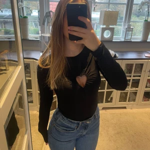 Svart långärmad topp med hjärtformad detalj - Säljer en svart långärmad body med en söt hjärtformad utskärning framtill. Storlek S🥰
