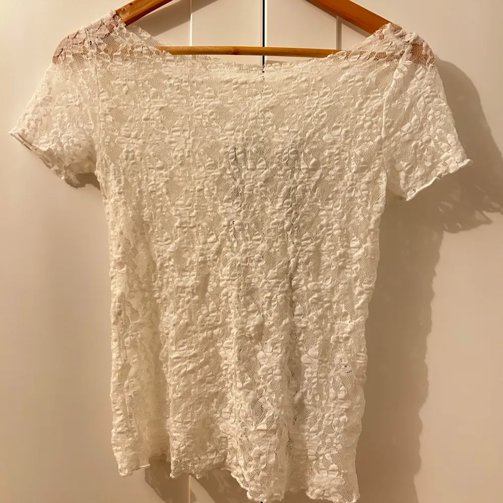 Säljer en superfin vit spetsblus i mycket bra skick. Den är kortärmad och har en elegant offshoulder-design. Perfekt för sommarens alla fester eller en mysig vårdag. Materialet är lätt och luftigt, vilket gör den bekväm att bära hela dagen. Kragen har jag själv klippt så att den är i offshoulder look. Köpt utomlands flera år sen aldrig kommit till användning. Mycket vitare färg än i bilden!!!. Toppar.