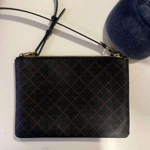 By Malene Birger väska - En superfin By Malene Birger väska i nästintill nytt skick! Väskan funkar som en clutsch och som axelbandsväska med ett på och avtagbart band. 