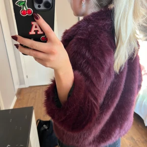 Vinröd pälsjacka - Säljer en supermjuk och fluffig vinröd pälsjacka. Den är perfekt för att hålla sig varm och snygg under hösten och vintern. Jackan har långa ärmar och stängs med knappar framtill. Den är i mycket bra skick och passar perfekt för både vardag och fest.