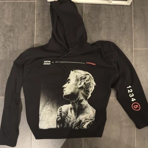 Svart hoodie med Justin Bieber-tryck från H&M - Säljer en svart hoodie från H&M med ett coolt Justin Bieber-tryck på framsidan. Texten 'CHANGES' i rött och '1234 (5)' på ärmen ger den en unik touch. Perfekt för alla Beliebers! 🖤 använd 2 gånger endast 