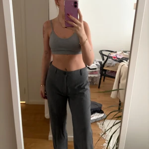 Grå byxor från Pull&Bear - Säljer ett par snygga grå byxor från Pull&Bear. De har en klassisk straight fit och är perfekta för både vardag och lite mer uppklädda tillfällen. Byxorna är i bra skick och har en stilren design med knäppning fram. Perfekta för höst och vår!