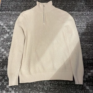 Beige stickad tröja från Zara - Säljer en snygg beige stickad tröja från Zara. Den har en dragkedja vid halsen och är perfekt för kyliga dagar. Tröjan är i mycket bra skick och passar både till vardags och lite finare tillfällen. Perfekt för höst och vinter!