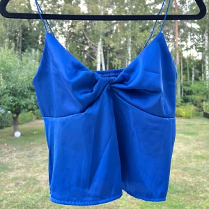 Blått satin-linne med tunna band - Gulligt mörkblått linne i satin. Stretchigt med tunna band. Normalt i storlek!  Aldrig använd 🥰  Längd: 46 cm Axel: 40 cm