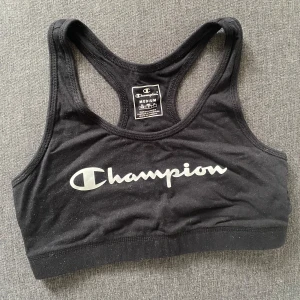 Svart bomullstopp från Champion - Säljer en svart bomullstopp från Champion i storlek medium. Toppen är ärmlös och har en klassisk brottarrygg. Den är gjord i ett mjukt och stretchigt material med Champion-loggan tryckt på framsidan.🤍 Skickas eller hämtas i Linköping. 📬