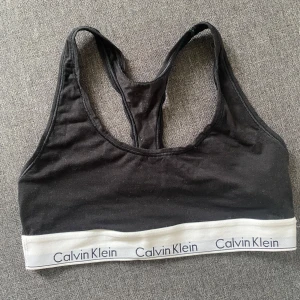 Svart sporttopp från Calvin Klein - Säljer en svart bomullstopp från Calvin Klein. Den har  en klassisk design med en brottar och ett elastiskt band med Calvin Klein-loggan i vitt. 🤍               Skickas eller hämtas i Linköping. 📬