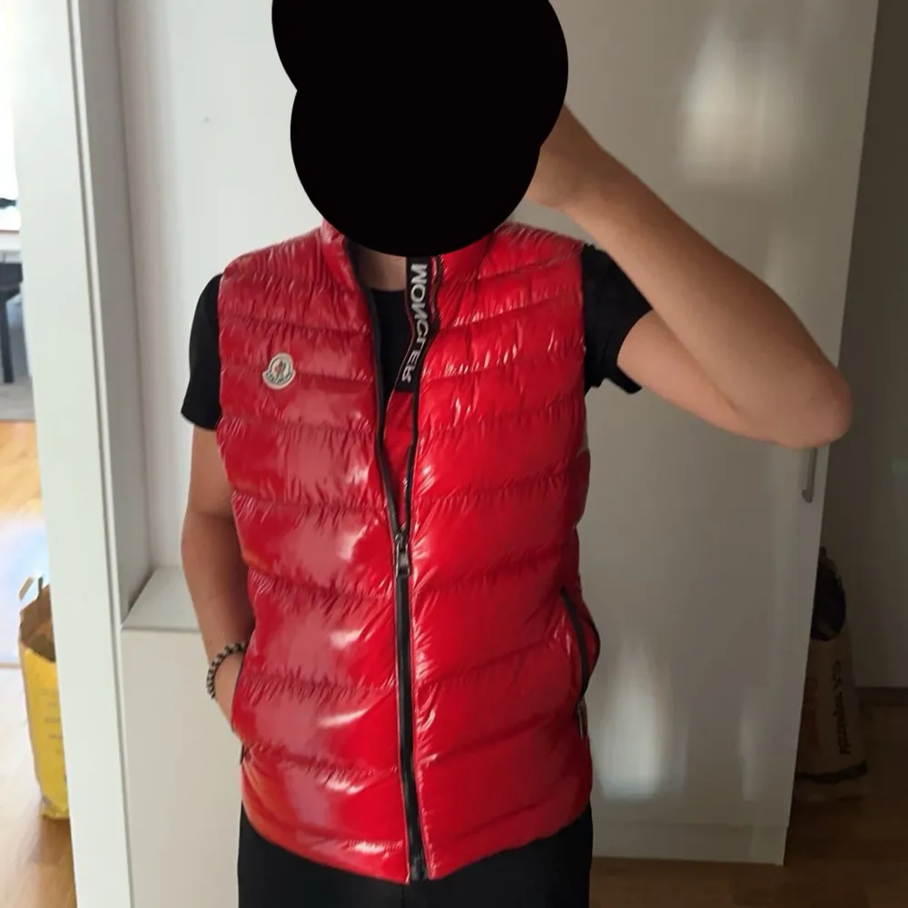 Säljer en snygg röd dunväst från Moncler i S. Västen är quiltad och har en glansig finish med dragkedja framtill. Perfekt för höst och vår när du vill hålla dig varm och stilren. Moncler-loggan syns tydligt på bröstet. lite problem i höger ficka. Jackor.