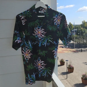 Skjorta från Kenzo - Kortärmad blommig skjorta från Kenzo, använd men i fint skick   Bortsett från blommorna är skjotan svart