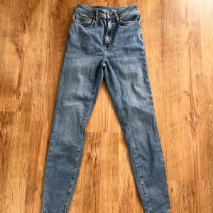 Blå jeans från Never Denim - Säljer ett par snygga blå jeans från Never Denim by Bik Bok. De är högmidjade och har en skinny passform som sitter tajt och bekvämt. Materialet är en mix av bomull, polyester och elastan vilket gör dem stretchiga och sköna att ha på sig. Perfekta för både vardag och fest!