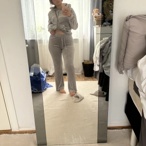 Grå velour hoodie - Säljer en supermysig grå hoodie i velourmaterial. Den har en dragkedja framtill och en justerbar huva med snören. Perfekt för en chill dag hemma eller när du vill vara bekväm men ändå snygg. Passar perfekt till höst och vinter! byxorna i xs och koftan i L