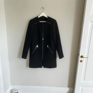 Svart kappa Zara  - Svart kappa från Zara köpt för många år sedan. Guldkedjor. Inga fel på kappan, som ny.  Black coat from Zara. Size S. 