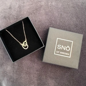 Halsband Snö of Sweden - Guldigt halsband med två droppformade smycken som pryds av små stenar. Halsbandet är aldrig använt.