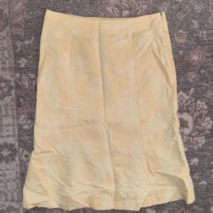 Vintage kjol  - Fin vintage kjol köpt på second hand. Ljusgul/beige med blommor som motiv och har en dragkedja. Storlek 36 från Lindex. Den har en liten fläck som syns på sista bilden men som säkert kan tas bort, utöver det i bra skick! 
