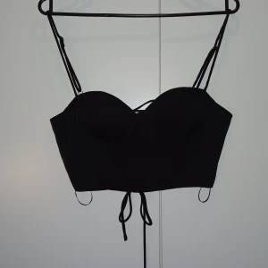 Svart kort topp - En svart kortare topp som passar perfekt när man vill klä upp sig. Den är väl använd men absolut inget som syns. Den är lite vaderad så ingen bh krävs under.