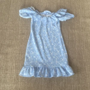 Blå blommig klänning från Gina Tricot - Söt blå klänning från Gina Tricot med ett fint blommigt mönster. Klänningen har offshoulder-stil och volangdetaljer vid fållen. Perfekt för sommarens fester eller en dag på stan!❤️❤️