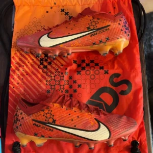 Nike mercurial Vapor 15 ag-pro storlek 42 26,5 cm  - Snygga röda fotbollsskor från Nike med svart och vit logga. Skorna har snörning och en iögonfallande design med svarta detaljer. Perfekta för fotbollsplanen. Det finns sprickor på dobbarna, påse ingår inte då jag gav den till en vän.