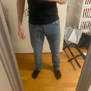 Jack&Jones jeans - Säljer ett par snygga blå jeans med tapered passform. De har en klassisk design med fem fickor och knappar i midjan. Använda en gång då jag köpte fel storlek. 