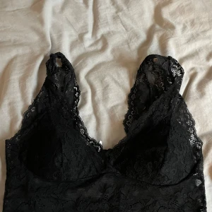 Svart spetslinne från Pieces - Snyggt svart spetslinne från Pieces i storlek S. Linnet har en elegant spetsdesign och är perfekt för att lägga till en touch av stil till din outfit. Passar bra under en kavaj eller som det är.