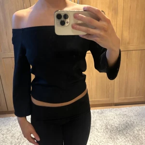Svart offshoulder topp - Snygg svart offshoulder topp med trekvartsärm. Perfekt för en stilren look. Passar bra till både jeans och kjol.