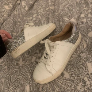 Vita sneakers med glittrig häl - Jag säljer vita sneakers med glittrig häl från ONLY. Skorna är använda men är i okej skick. Det är en repa på framsidan av ena skon och hål i slulorna vid hälen. Skorna kostar nyköpta 400kr.