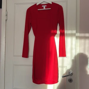 Röd klänning med öppen rygg - Snygg röd klänning med långa ärmar och en elegant rynkdetalj på baksidan. Klänningen har en tight passform och är perfekt för en kväll ute. Den är tillverkad i ett mjukt och stretchigt material som ger en bekväm känsla. Är väldigt fin på
