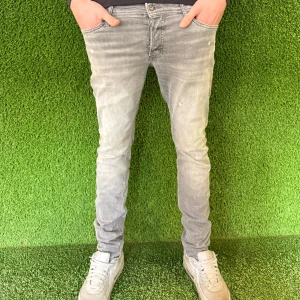 Grå Slim jeans - Snygga grå skinny jeans med en modern passform. De har en klassisk femficksdesign och är perfekta för en stilren look. Dragkedja och knapp framtill.