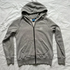 Adidas jacka  - Superfin grå adidas jacka med tryck på fram och baksidan Lite av dragkedjan har gått av men den funkar fortfarande! Vid köp av flera varor får du rabatt 💛