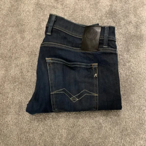 Mörkblå jeans från Replay - Snygga mörkblå jeans från Replay med klassisk femficksdesign och stilrena sömmar. Perfekta för en avslappnad look. Märkeslogga på baksidan av midjan. D’en lite sliten mellan benen. Priset kan diskuteras!