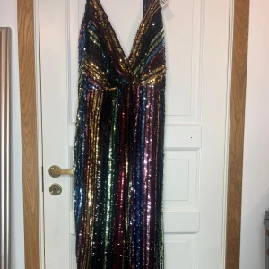 Flerfärgad paljettklänning från NLY Eve - Säljer en fantastisk långklänning från NLY Eve med glittrande paljetter i regnbågens alla färger. Klänningen har en djup v-ringning och smala axelband, 