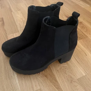 Svarta boots i mocka - Snygga svarta boots i mocka med en robust klack och elastiska paneler på sidorna för enkel på- och avtagning. Perfekta för en stilren look. Aldrig använt, köpt för 499 säljer för 200