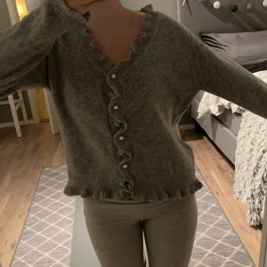 Grå kofta med volangdetaljer - Mysig grå kofta med knappar, jätteskönt material! Står ingen storlek men den passar mig som har XS/S vanligtvis💗