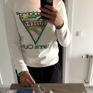 Vit långärmad tröja med tennistryck - casablanca tröja, Säljer en vit långärmad tröja med ett färgglatt tennistryck på framsidan. Perfekt för den som gillar sportig stil. Tröjan har en rund hals och är i en bekväm passform. Sitter som L 