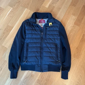 Svart pufferjacka från Parajumpers barn för 10 år gamla  - Säljer en snygg svart pufferjacka från Parajumpers med quiltad design och dragkedja framtill. Jackan har långa ärmar och ribbade muddar. Perfekt för kyligare dagar med sin kombination av fleece och puffer-material.