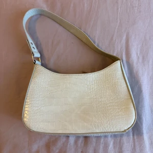 Mint axelväska med krokodilmönster - Snygg mint axelväska med krokodilmönster. Väskan har en justerbar axelrem med nitar och en stilren design. Perfekt för att ge din outfit en trendig touch.