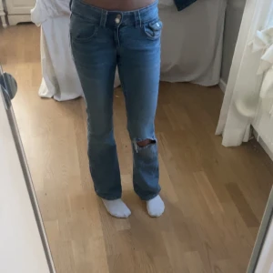Ljusblå lågmidjade bootcut jeans från Gina  - Snygga blå jeans från Gina med en snygg slitning på ena benet. De har fina detaljer och är i bra skick. 
