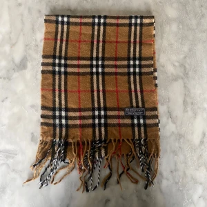 Beige burberry halsduk  - Skick: 8/10. Halsduken är i bra skick och har inga defekter. Mått: 147cm x 28cm