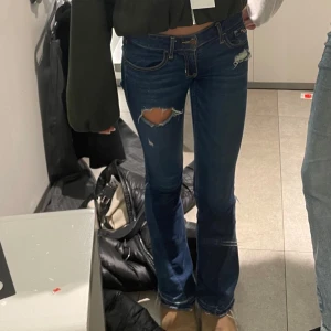 Blå bootcut jeans från Hollister - Snygga blå bootcut jeans från Hollister med slitna detaljer på låren. De har en klassisk femficksdesign och är perfekta för en avslappnad stil. Passar bra till både sneakers och boots. Det går alltid att diskutera om pris🥰❤️