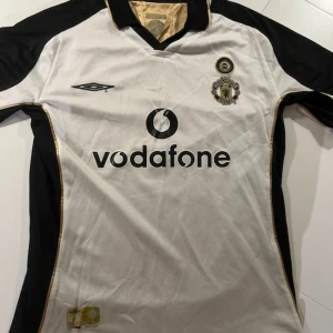 Manchester United limeted edition 2001-2003 fotbollströja  - En väldigt unik Manchester United som dom hade för att fira 100 år. Denna är köpt 2002, det är 6/10 i skick men de finns knappt denna tröja i bättre skick någon stans. Den är på framsidan vit men om du vänder ut o in på den blir det en guldig tröja.