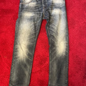 Blå tvättadd Nudie Jeans - Säljer ett par snygga blå jeans från Nudie Jeans i storlek 34/34. De har en klassisk straight fit och är i bra skick med coola slitningar för en snygg look. 
