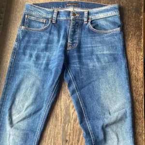 Riktigt snygga Nudie Jeans  - Size 32/32, slim fit. Har en mellanblå färg, på bilden ser de lite ljusare ut. Har använt dem ett antal gånger men de är nästan som nya. 