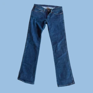 Blå jeans från Wrangler - Säljer ett par klassiska blå jeans från Wrangler. De har en bootcut-stil och är i mycket bra skick. Perfekta för både vardag och fest! Jeansmaterialet är slitstarkt och bekvämt. Storleken är dam M.